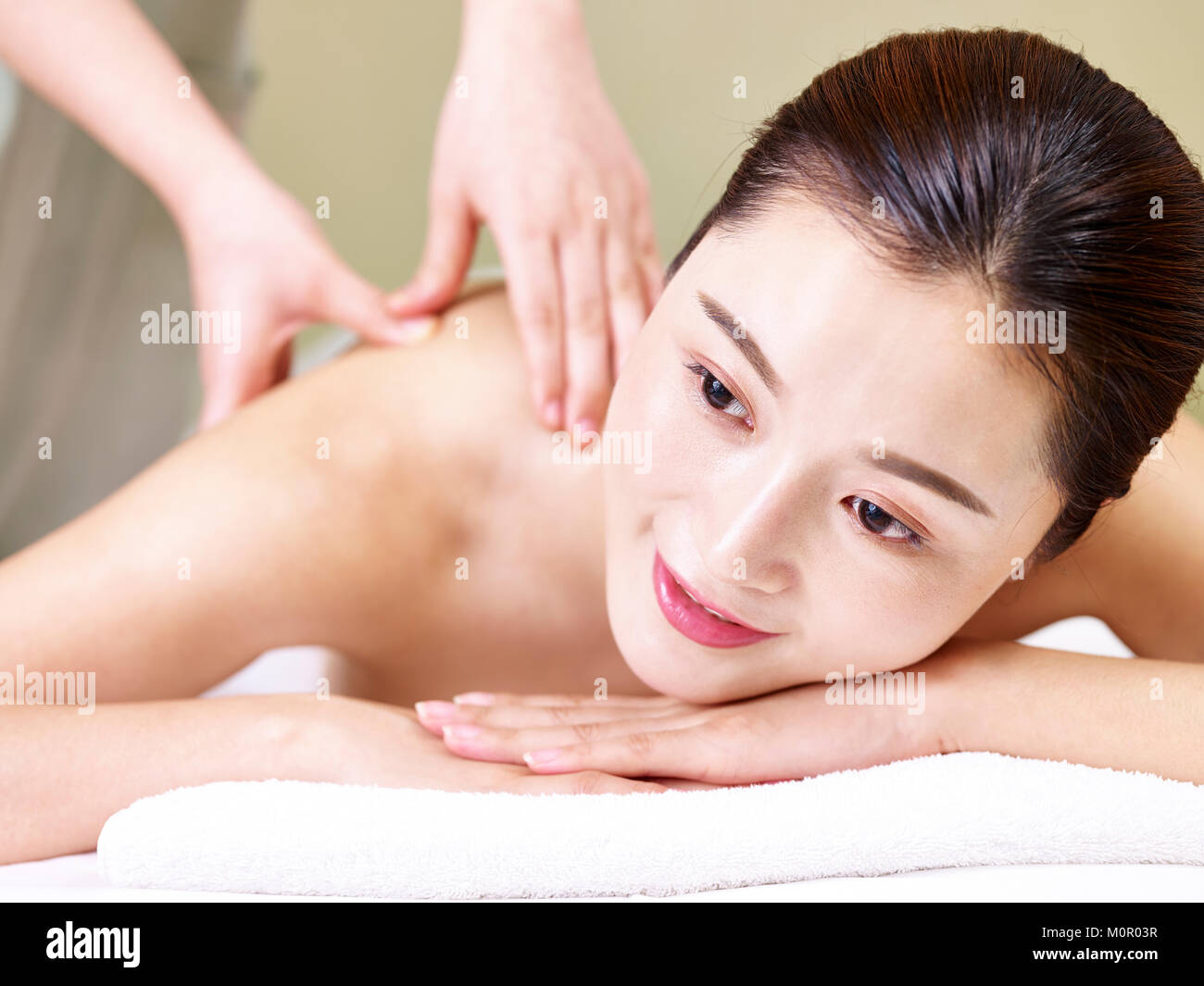 Nahaufnahme des Gesichts eines schönen jungen asiatischen liegende Frau auf der Vorderseite auf dem Bett, die Massage in der Spa. Stockfoto