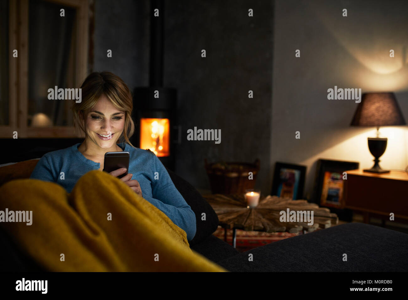 Porträt der lächelnde Frau mit Smartphone auf der Couch entspannen am Abend Stockfoto