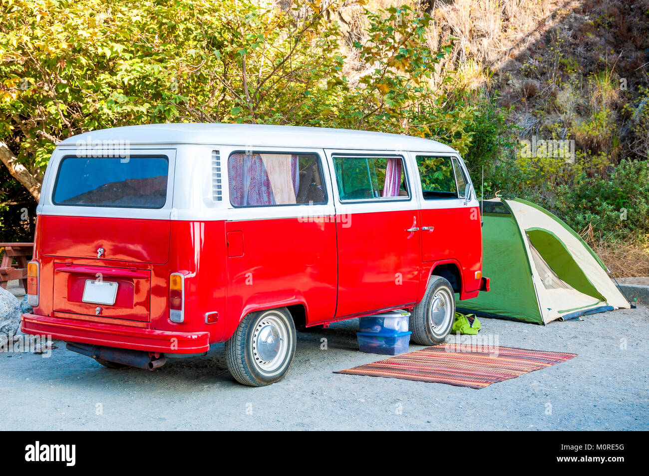 Strand Campingplatz mit roten hippie Minibus, grüne Zelt und rustikalen Wolldecke/Hippie lifestyle Konzept Stockfoto