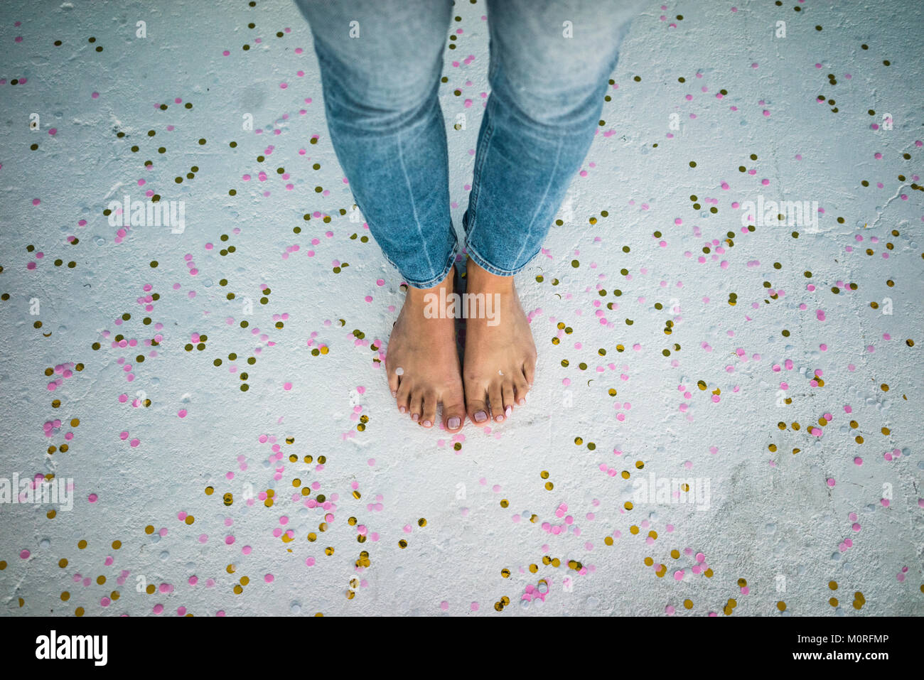 Füße der jungen Frau, die zwischen Konfetti auf dem Boden Stockfoto