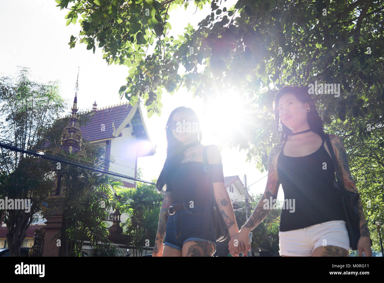 Asiatische lesbisches Paar gehen mit halten die Hände auf der Straße mit Sonnenlicht. Stockfoto