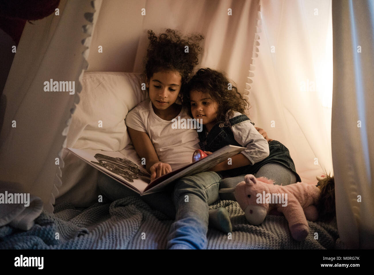 Zwei Schwestern im dunklen Zimmer sitzen, ein Buch zu lesen Stockfoto