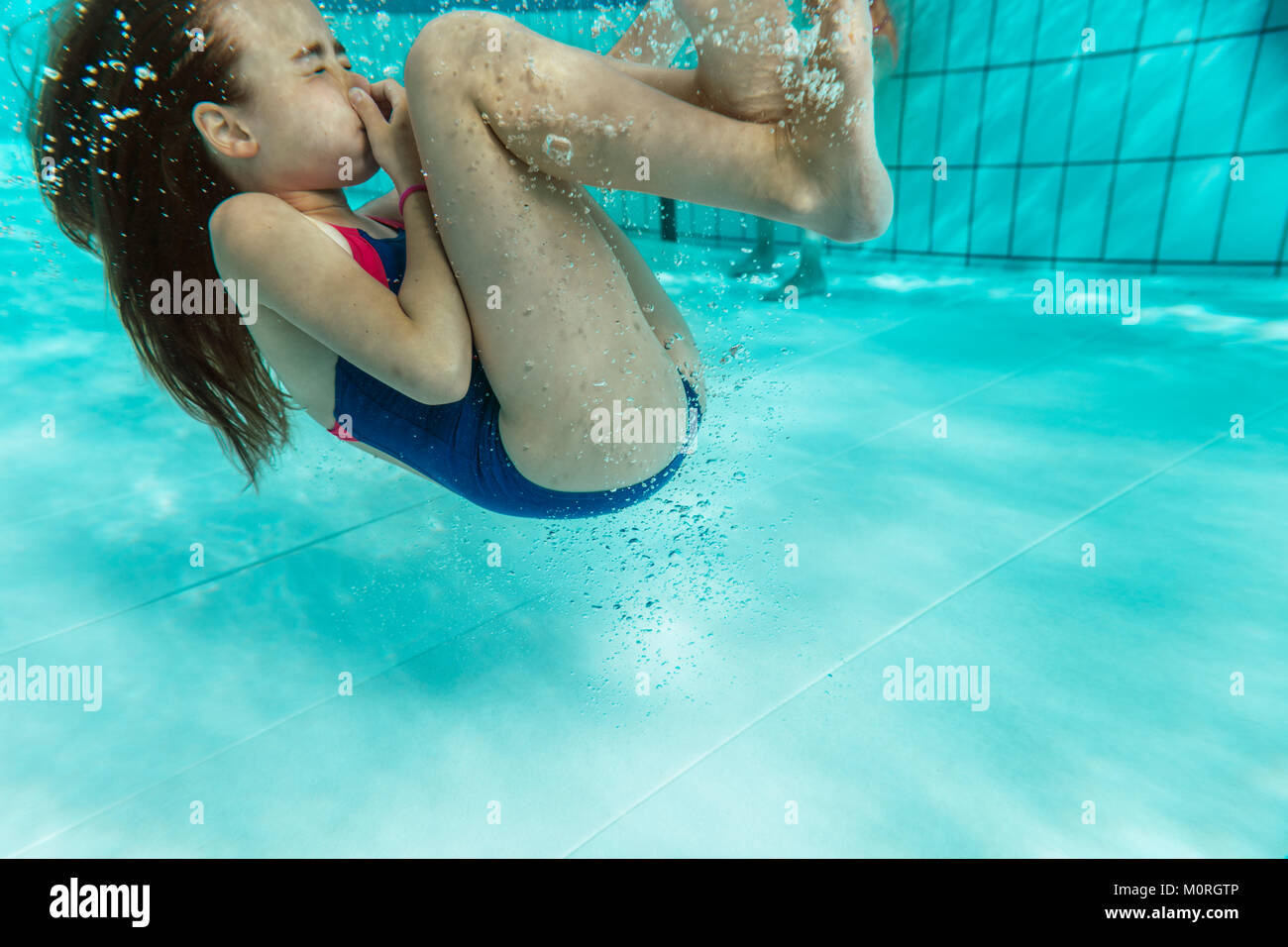 Mädchen tun eine Rolle unter Wasser im Pool Stockfoto