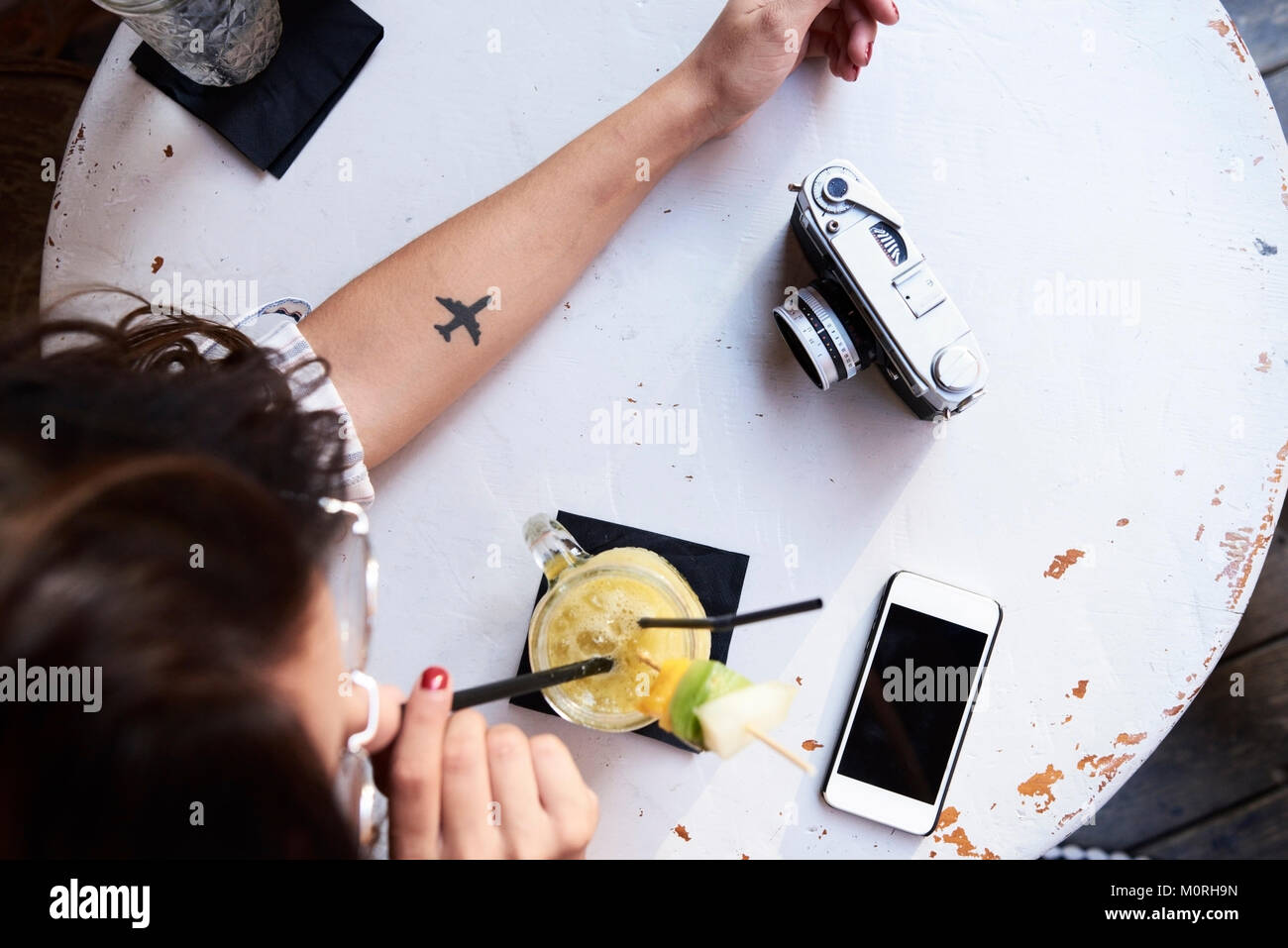 Overhead einer Ebene Tattoo, einen Film, Kamera, Telefon und ein Mädchen trinken pinneapple Smoothie. Stockfoto