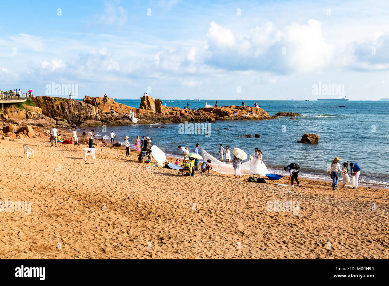 06-08-2016 - Qingdao, China - Fotografen die Hochzeit Alben Fotos auf viele Paare in taiping Bay Beach Stockfoto