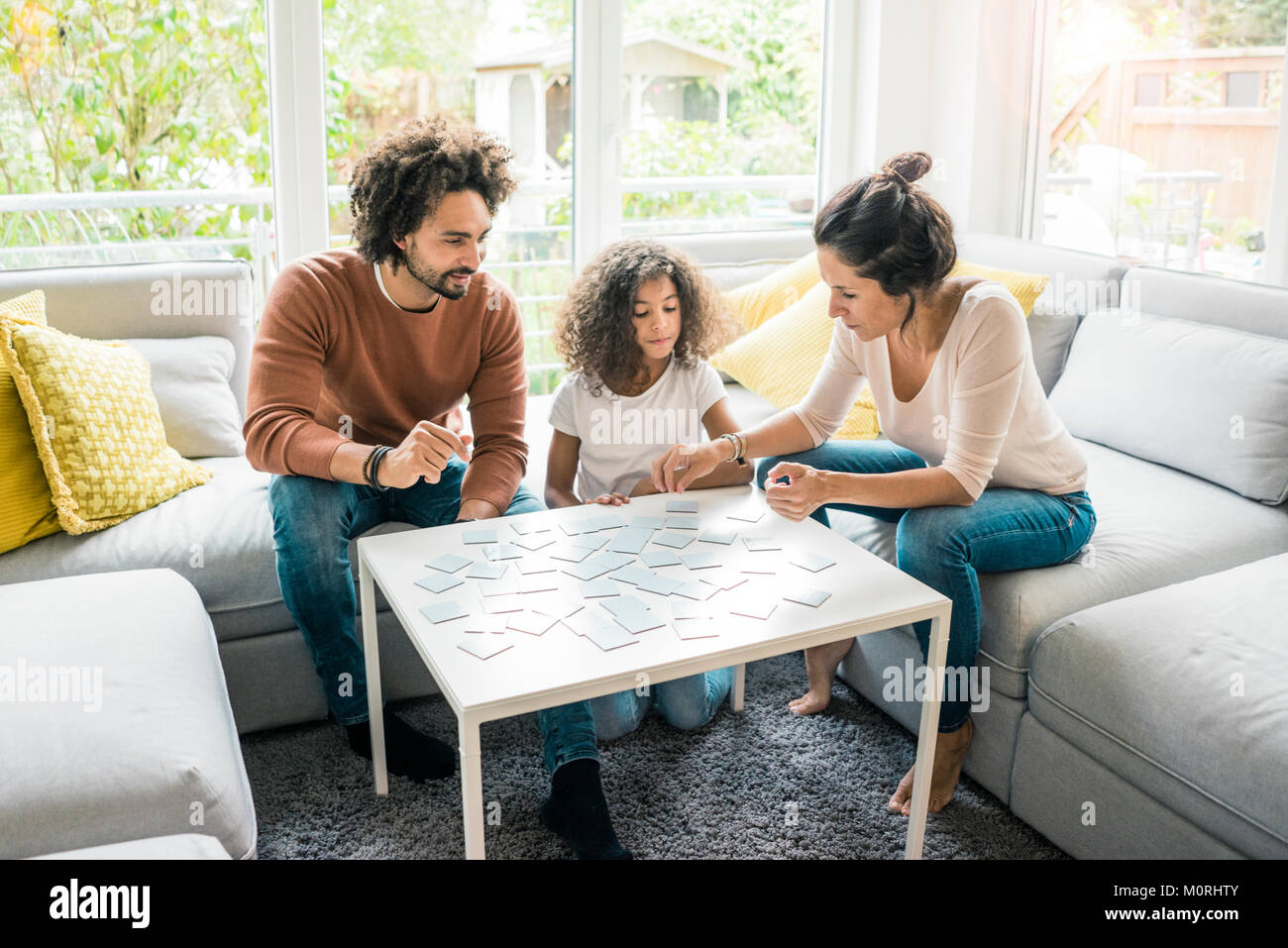 Familie sitzt auf der Couch und spielt Memory Spiel Stockfoto