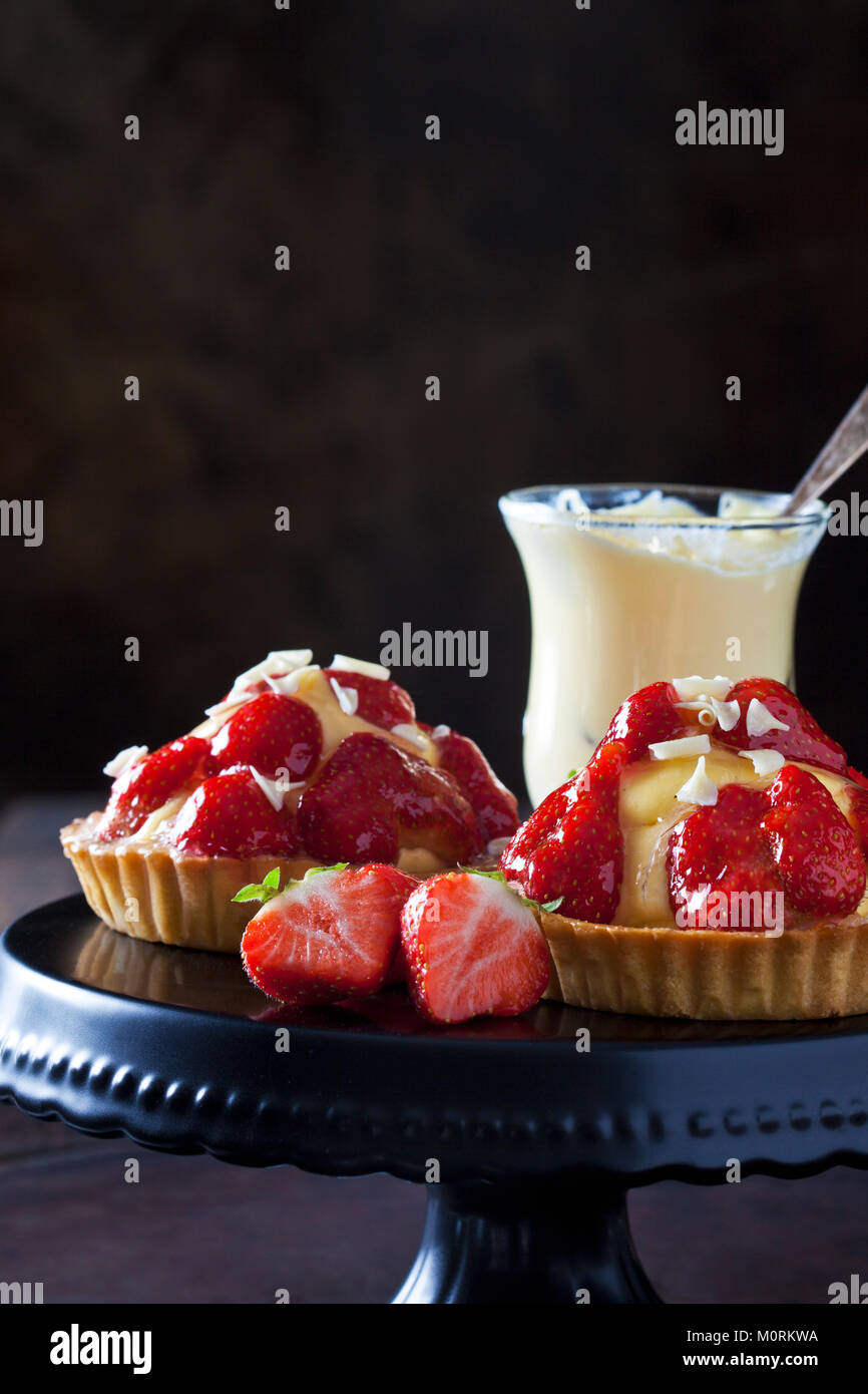 Zwei Erdbeere Törtchen mit Vanillepudding und weiße Schokolade rasieren auf Kuchen stand Stockfoto