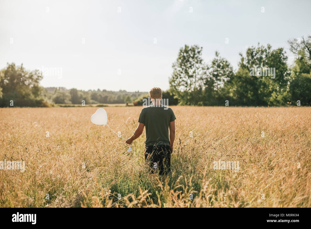 Junger Mann mit weissen Ballons in Herzform Stockfoto