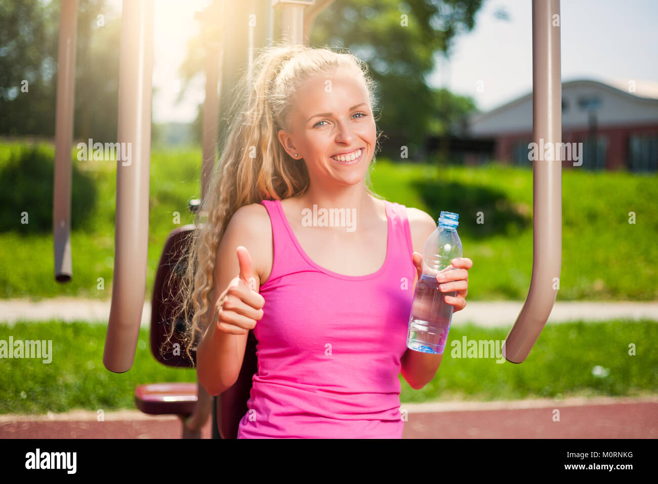 Junge Frau ausübt, im Fitnessbereich im Freien. Sie ist Trinkwasser. Stockfoto