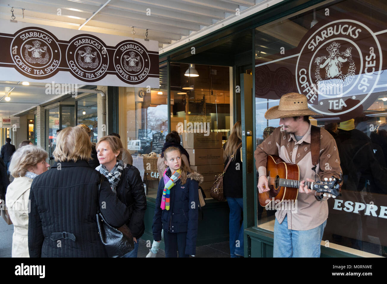 Ein strassenmusikant, Blickkontakt mit einem Mädchen vor Starbucks Kaffee, Pike Place Market, Seattle, Washington Stockfoto