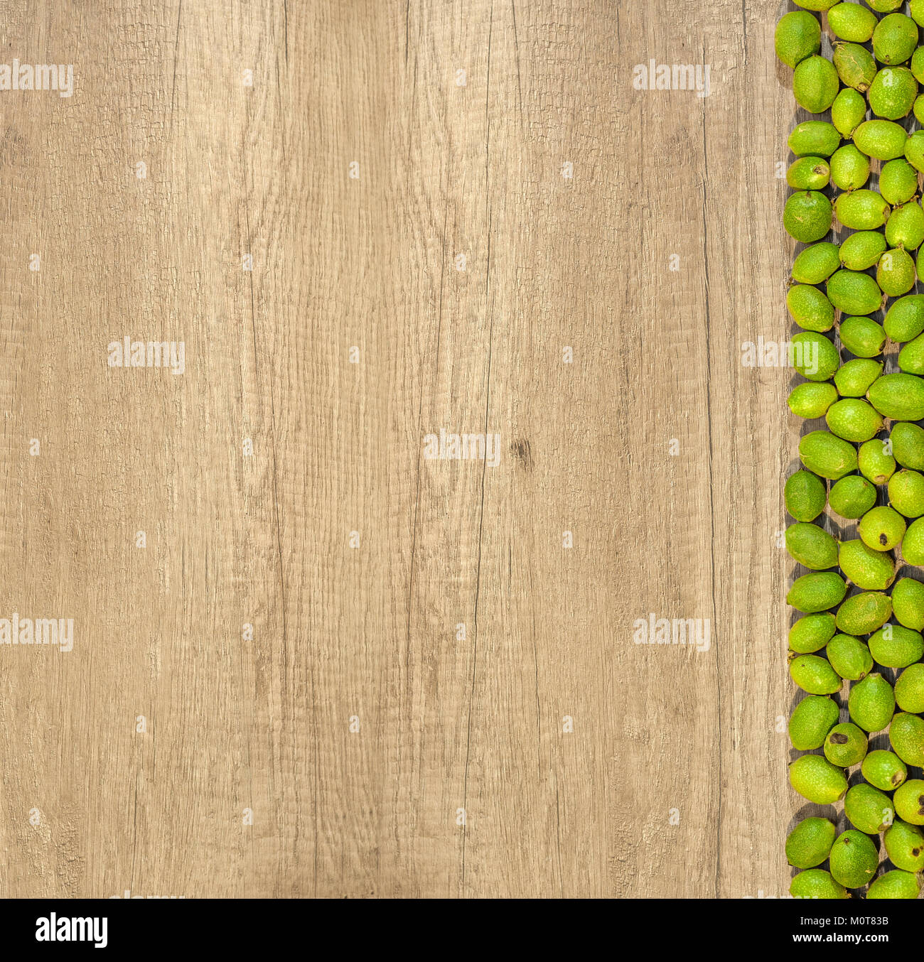 Grüne junge Walnüsse in Schalen auf der Seite zwei Reihen auf der hölzernen Tisch Stockfoto