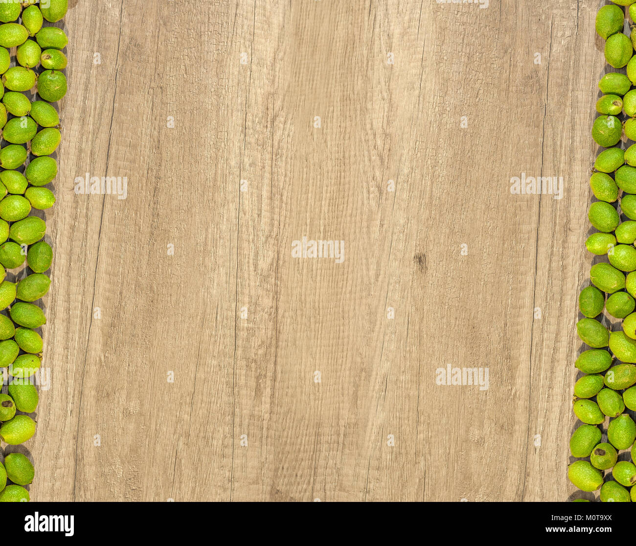 Grüne junge Walnüsse in Schalen auf der Seite zwei Reihen auf der hölzernen Tisch Stockfoto