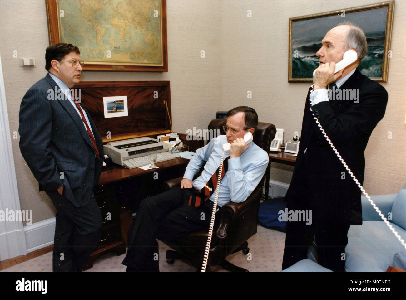 Präsidenten der Vereinigten Staaten George H.W. Bush spricht mit US-Außenminister James A. Baker, III, von seiner Studie im Oval Office des Weißen Hauses in Washington, DC am 17. Januar 1991. Im Bild von links nach rechts: Stabschef im Weißen Haus John Sununu, der Präsident, und dem nationalen Sicherheitsberater Brent Scowcroft. Obligatorische Credit: David Valdez/White House über CNP/MediaPunch Stockfoto