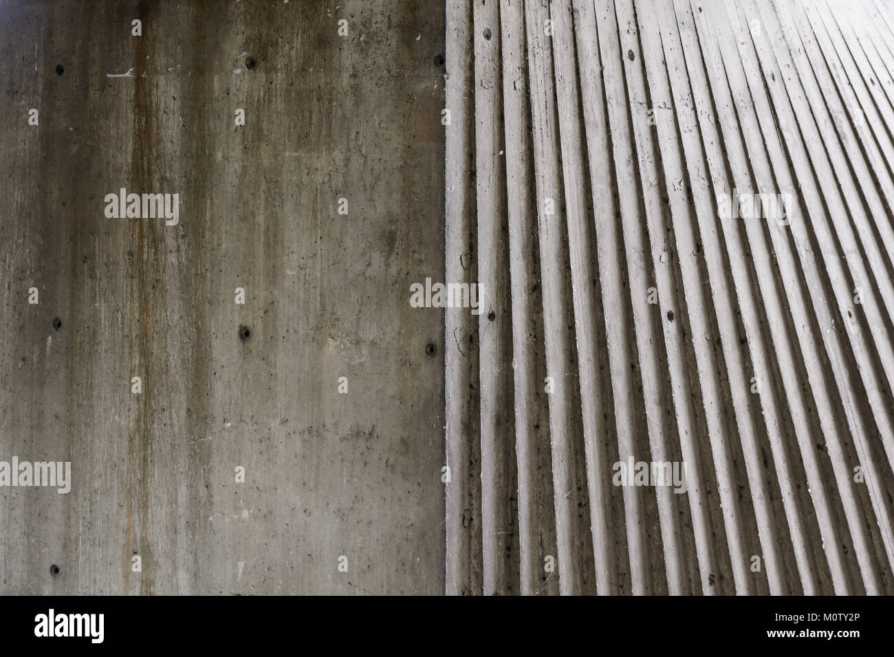 Abstrakte Sicht der Oberfläche einer konkreten Struktur, zur Hälfte glatt, zur Hälfte genutet, unter einem seitenlicht. Stockfoto