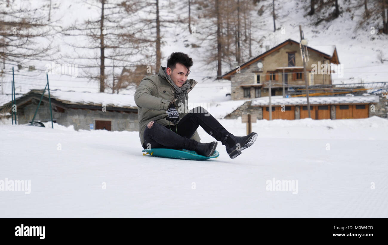 Junger Mann reiten Schnee Untertasse Stockfoto