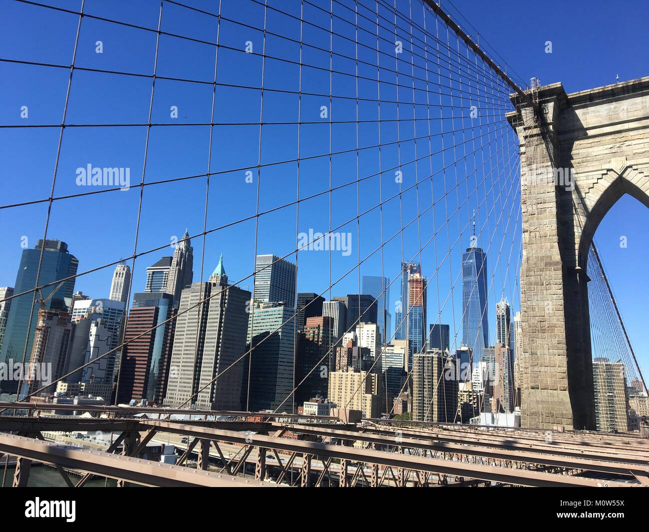 Blick auf Lower Manhattan im Hintergrund von oben auf die Brooklyn Bridge durch seine robuste bridgewires im Fokus. Stockfoto