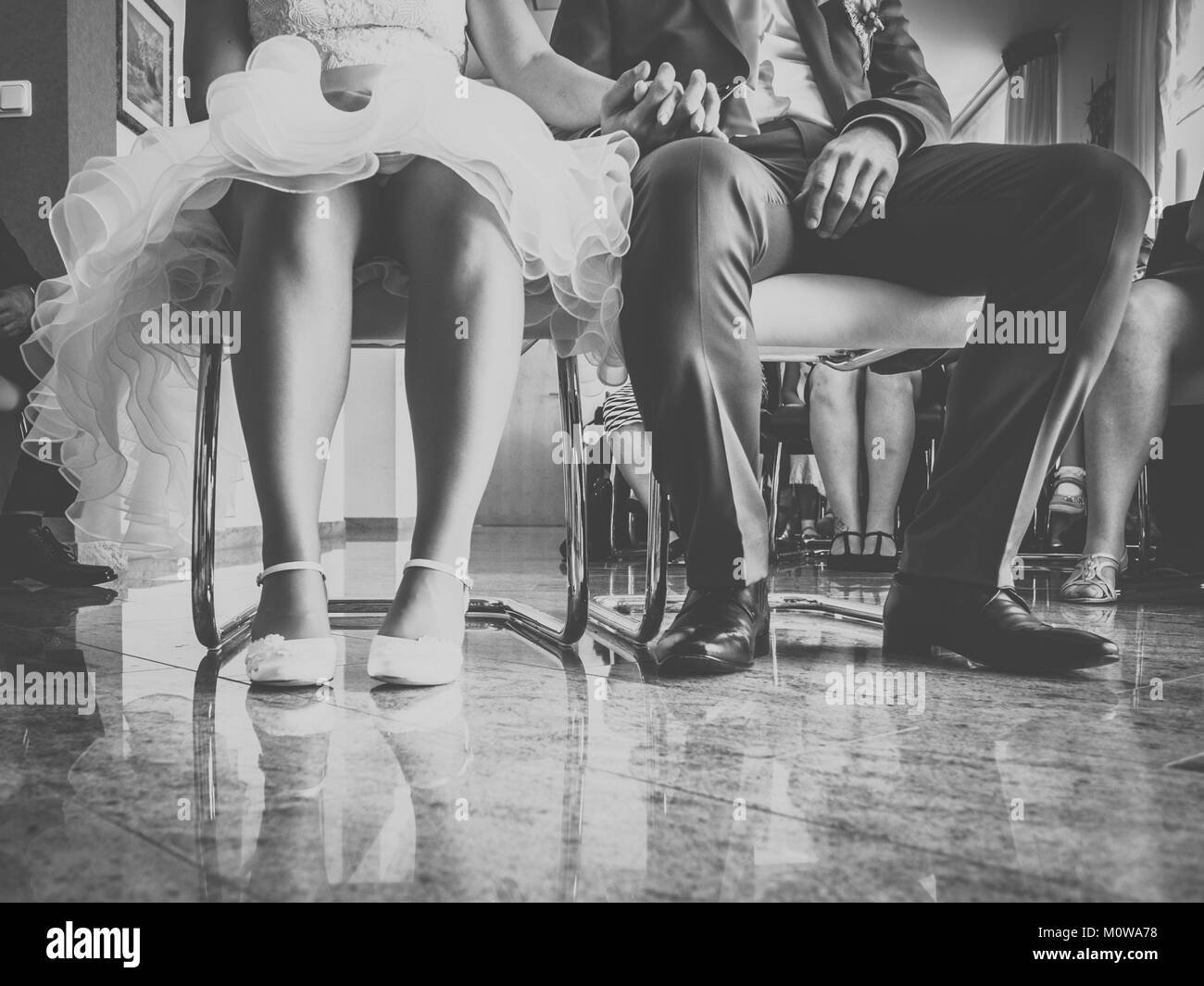 Die Braut und der Bräutigam sitzt auf dem Stuhl in der Registry Office in Schwarz und Weiß Stockfoto