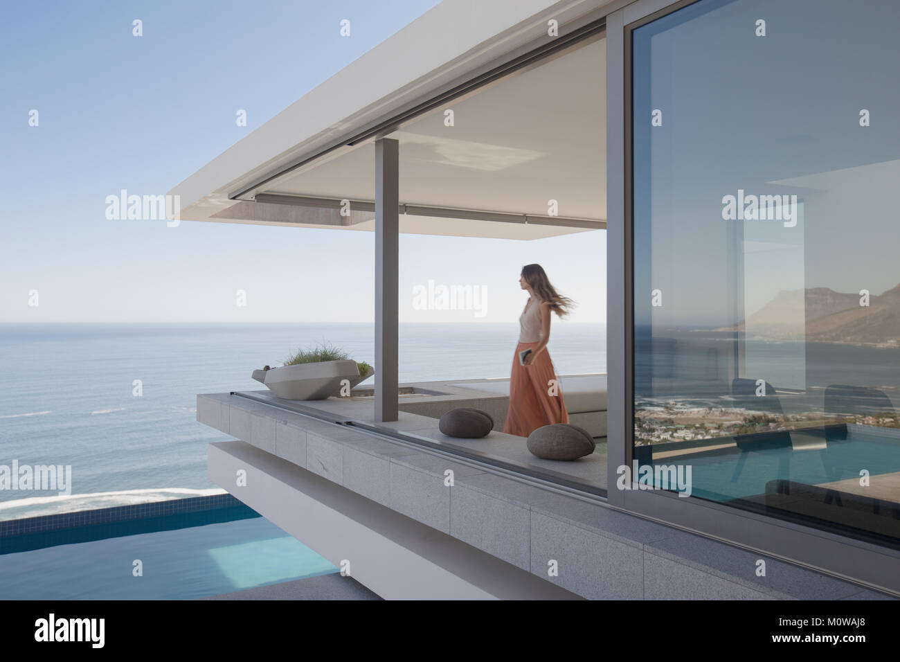 Frau mit Blick auf das Meer Blick auf moderne, luxuriöse Home Showcase außen Balkon Stockfoto