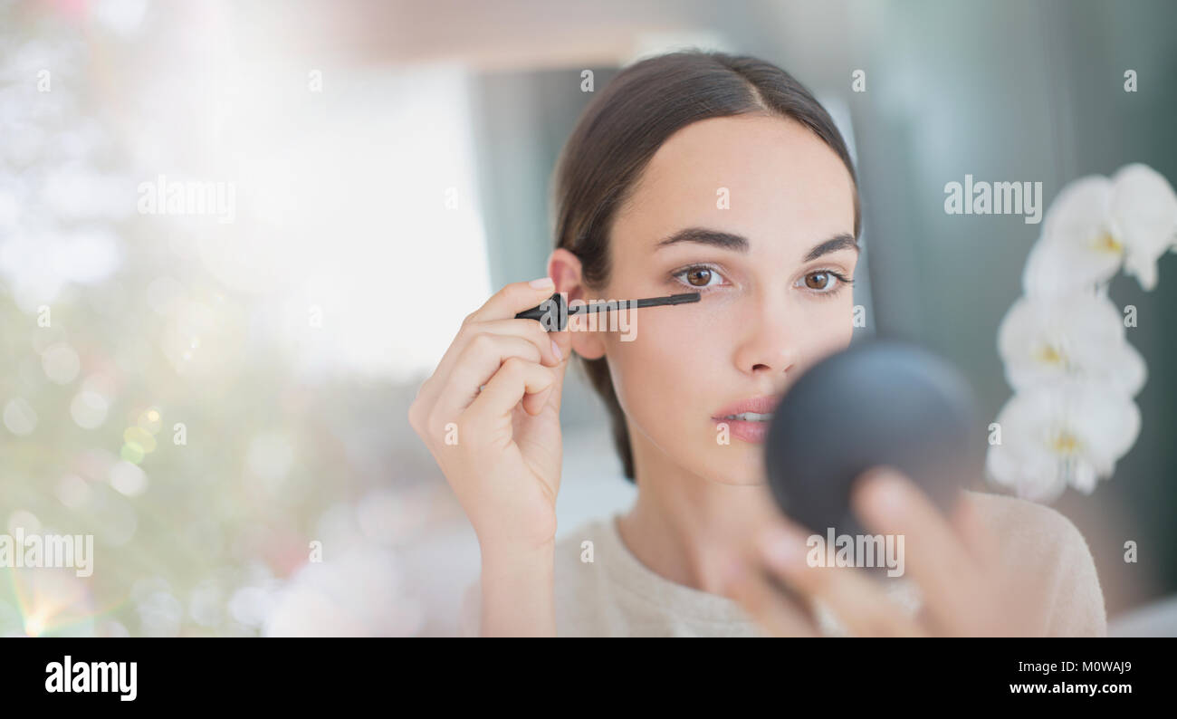 Frau gelten Mascara mit Mascara, Zauberstab und kompakte Spiegel Stockfoto