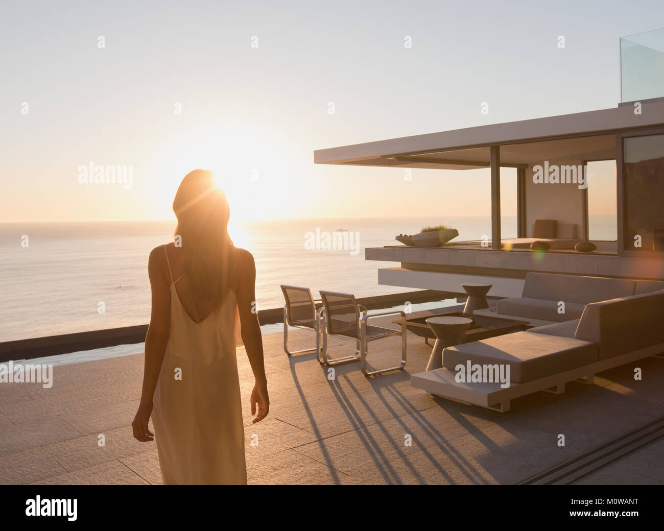 Frau gehen auf ruhigen Sunset moderne und luxuriöse Home Showcase äußere Terrasse mit Meerblick Stockfoto