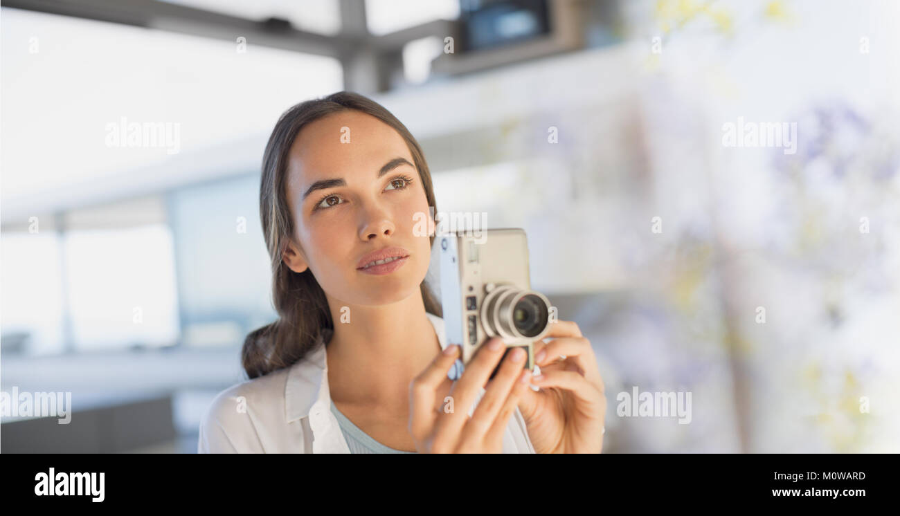 Ernsthafte brünette Frau mit Digitalkamera Stockfoto