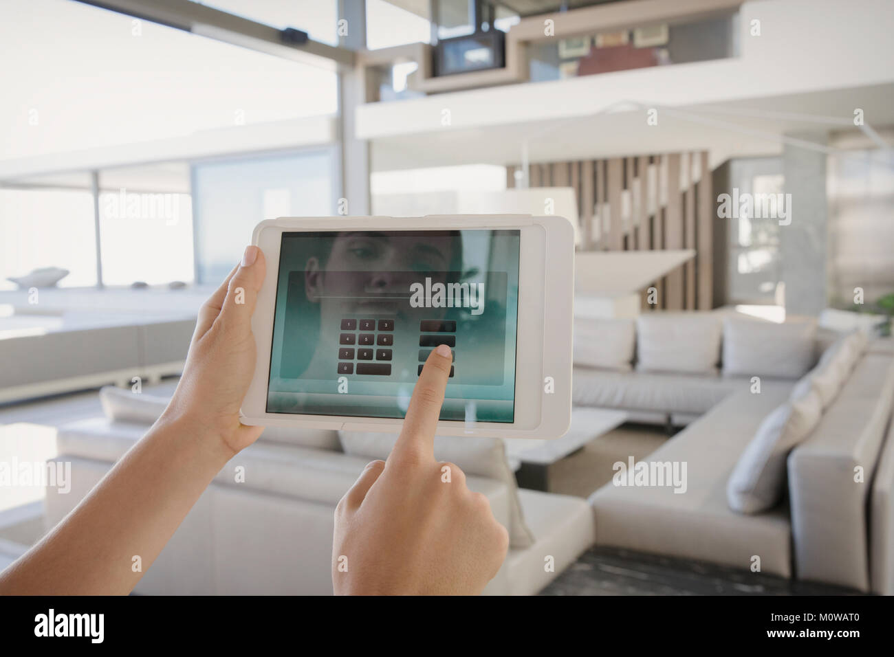 Persönliche Perspektive Frau mit digitalen tablet Managing Digital Security System in modernen, luxuriösen Home Showcase interior Wohnzimmer Stockfoto