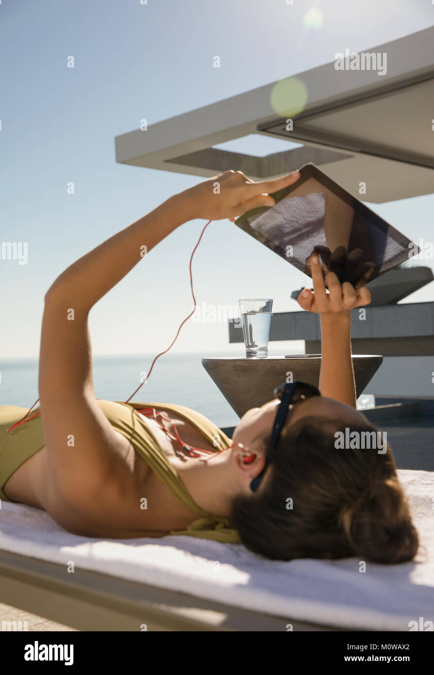 Frau sonnenbaden, mit digitalen Tablette auf Lounge Chair auf der sonnigen Terrasse Stockfoto