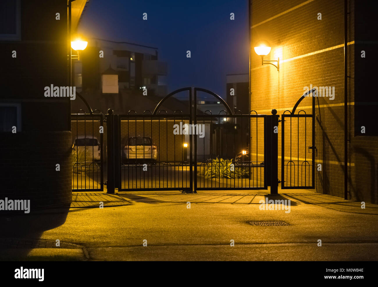 Gates und Bewegungssensitive Sicherheit Beleuchtung am Eingang zu einem privaten Parkplatz in Großbritannien. Stockfoto