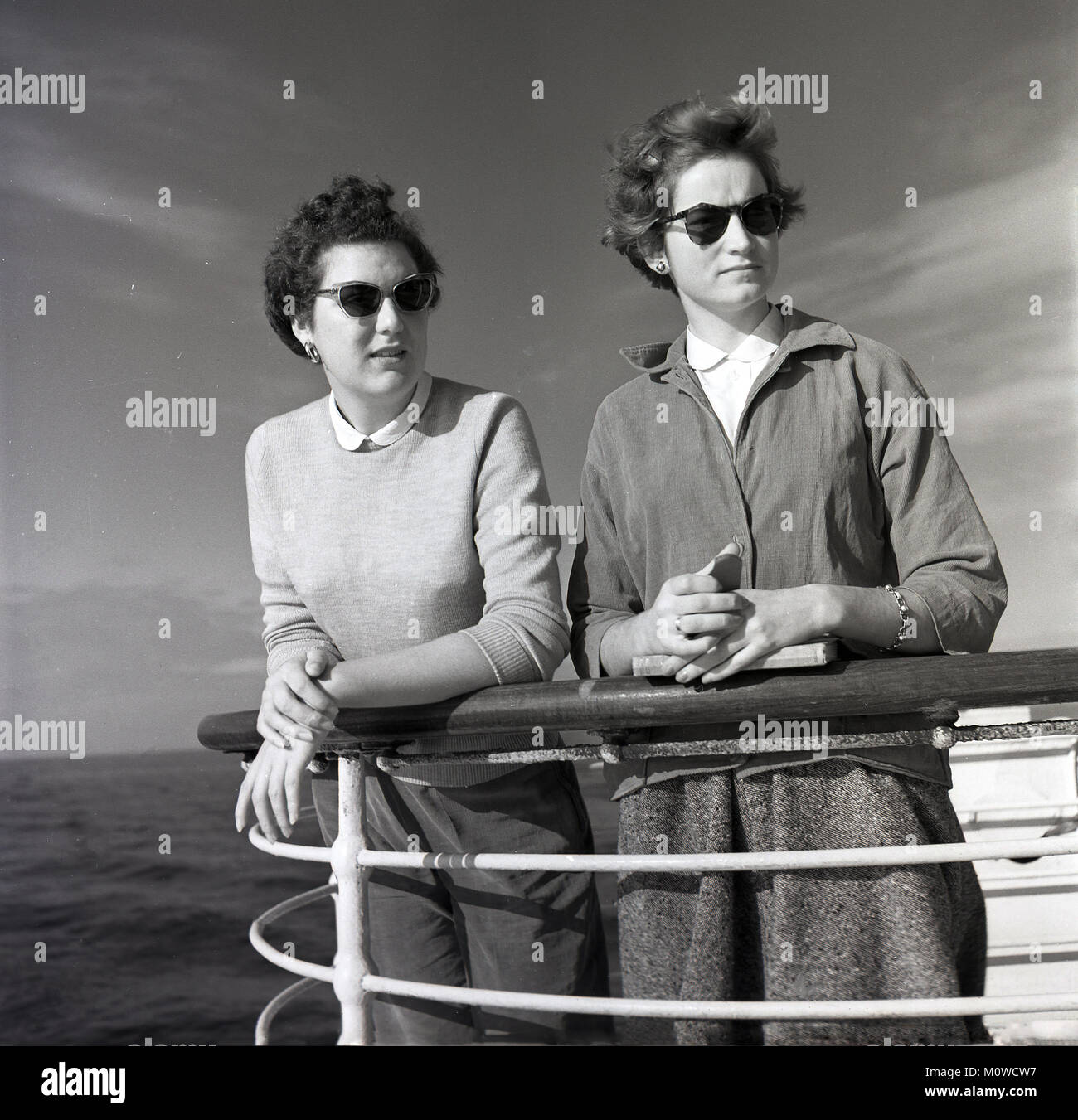 1950er Jahre, historische Bild von zwei junge Frau lehnte sich auf ein Geländer oder Handlauf an Deck eines Union-Castle Steamship, wie Sie über das Meer schauen, wie das Schiff segelt für das Kap in Südafrika. Diese Dampfer nahm Fracht, Post und Fluggäste übersee mit viele von denen an Bord gehen, ein neues Leben zu weg von der Schwermut des post Start-Krieg Großbritannien Stockfoto