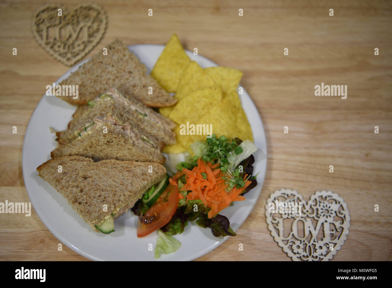 Essen Fotografie eines Mittag essen mit Thunfisch in Dosen und Gurke Sandwiches mit braunem Brot und gesunden Seite Salat auf Holz Hintergrund gemacht Stockfoto