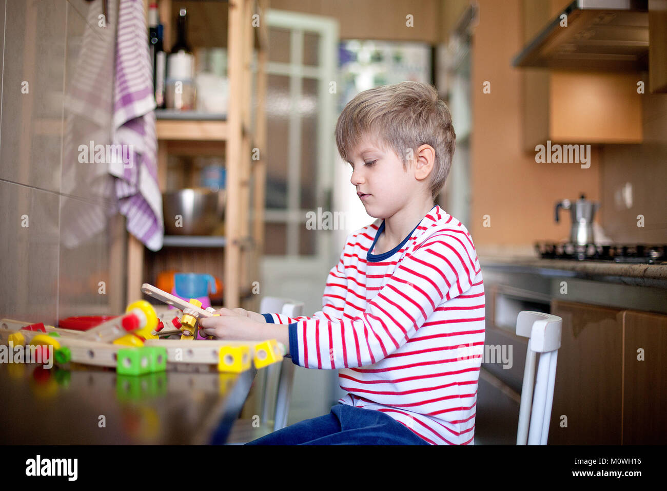 Junge mit gestreiften Schlafanzug spielen in der Küche mit seiner Konstruktion Spielzeug Stockfoto