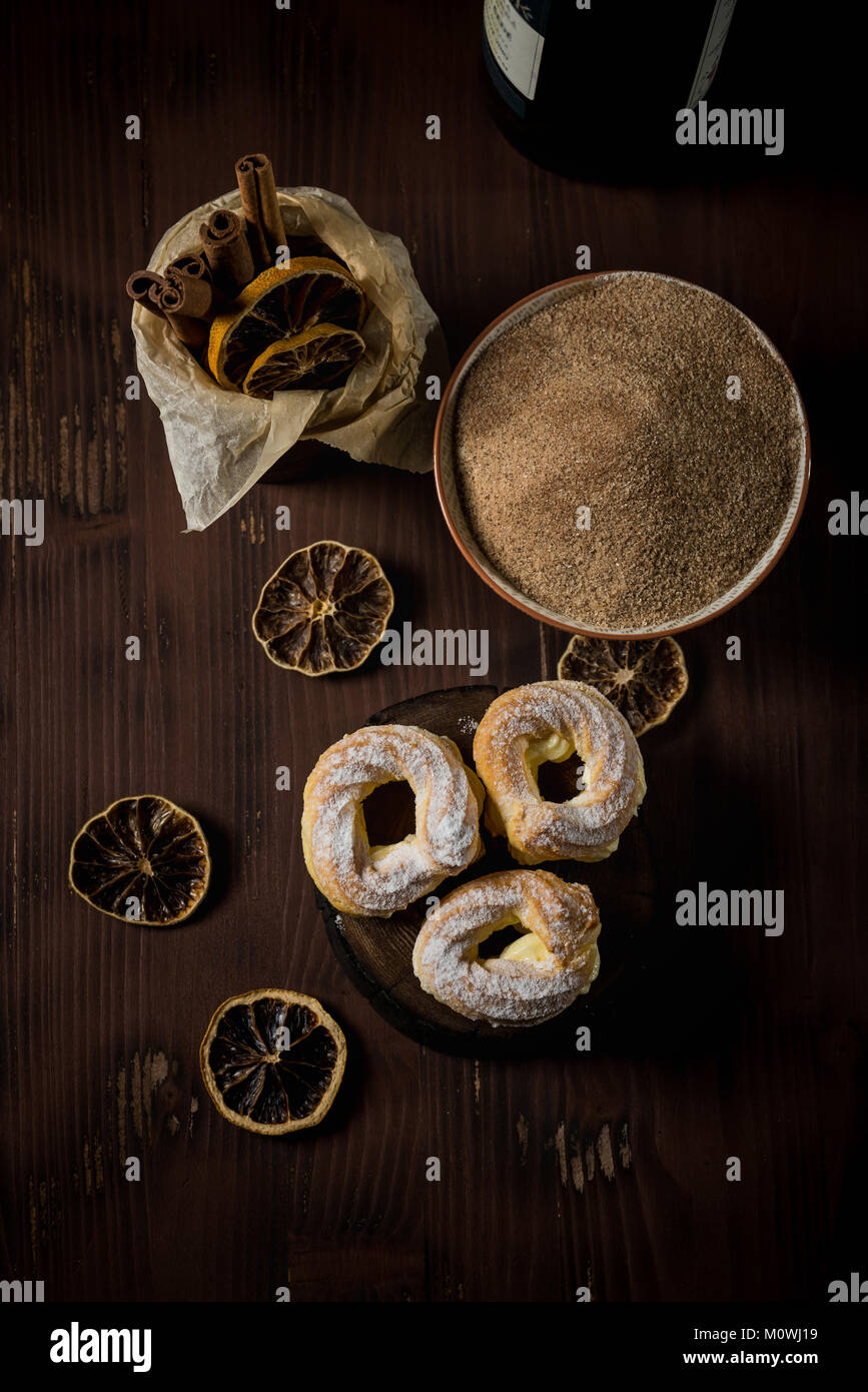 Vertikale Foto mit Top Aussicht auf drei hausgemachter Windbeutel. Süße Kuchen mit Sahne gefüllt und dunklem Holz Brett angeordnet mit einer Flasche Rotwein Stockfoto