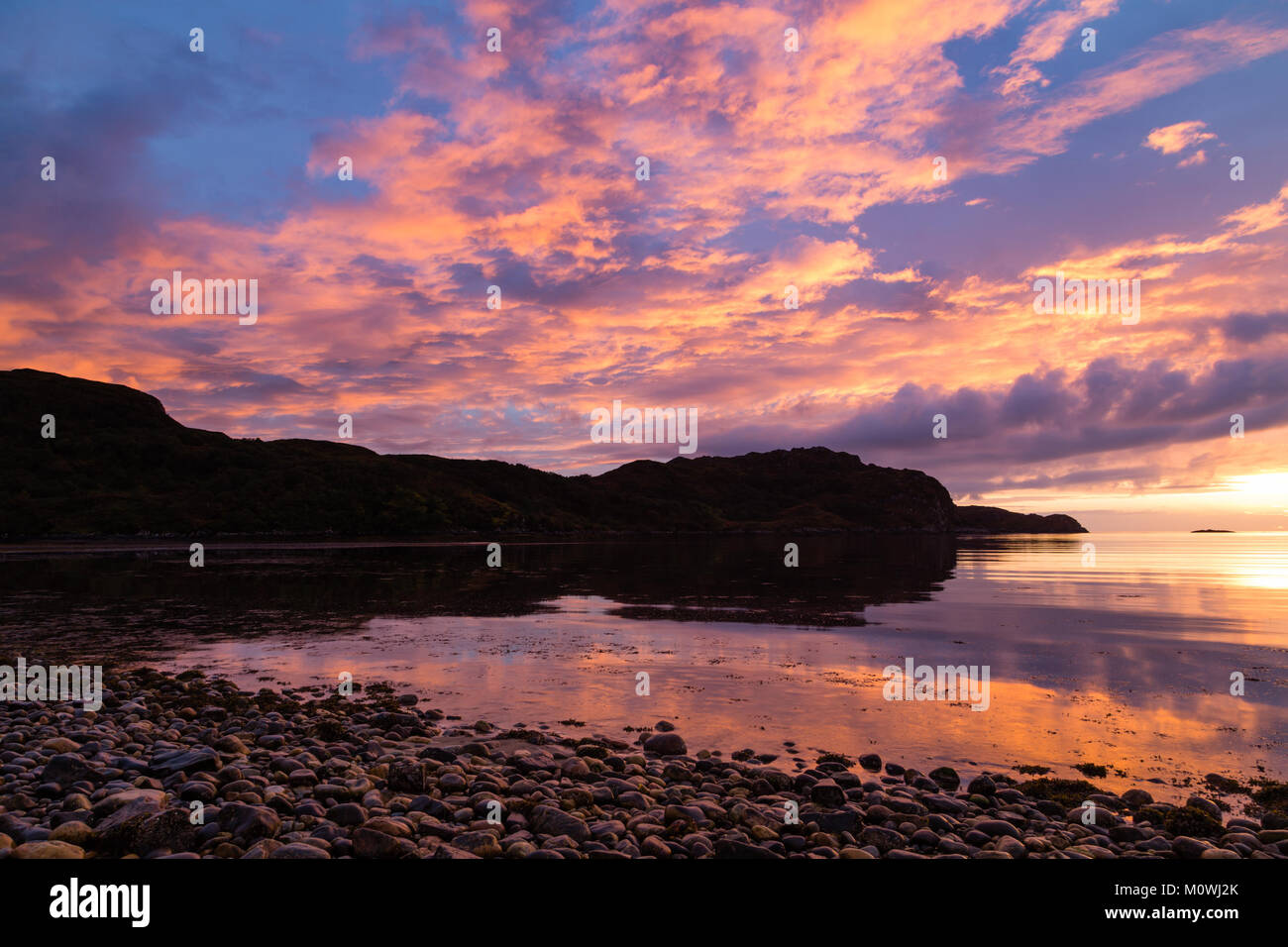 Orange Sky reflektiert über das Wasser bei Inverkirkaig bei Sonnenuntergang Stockfoto