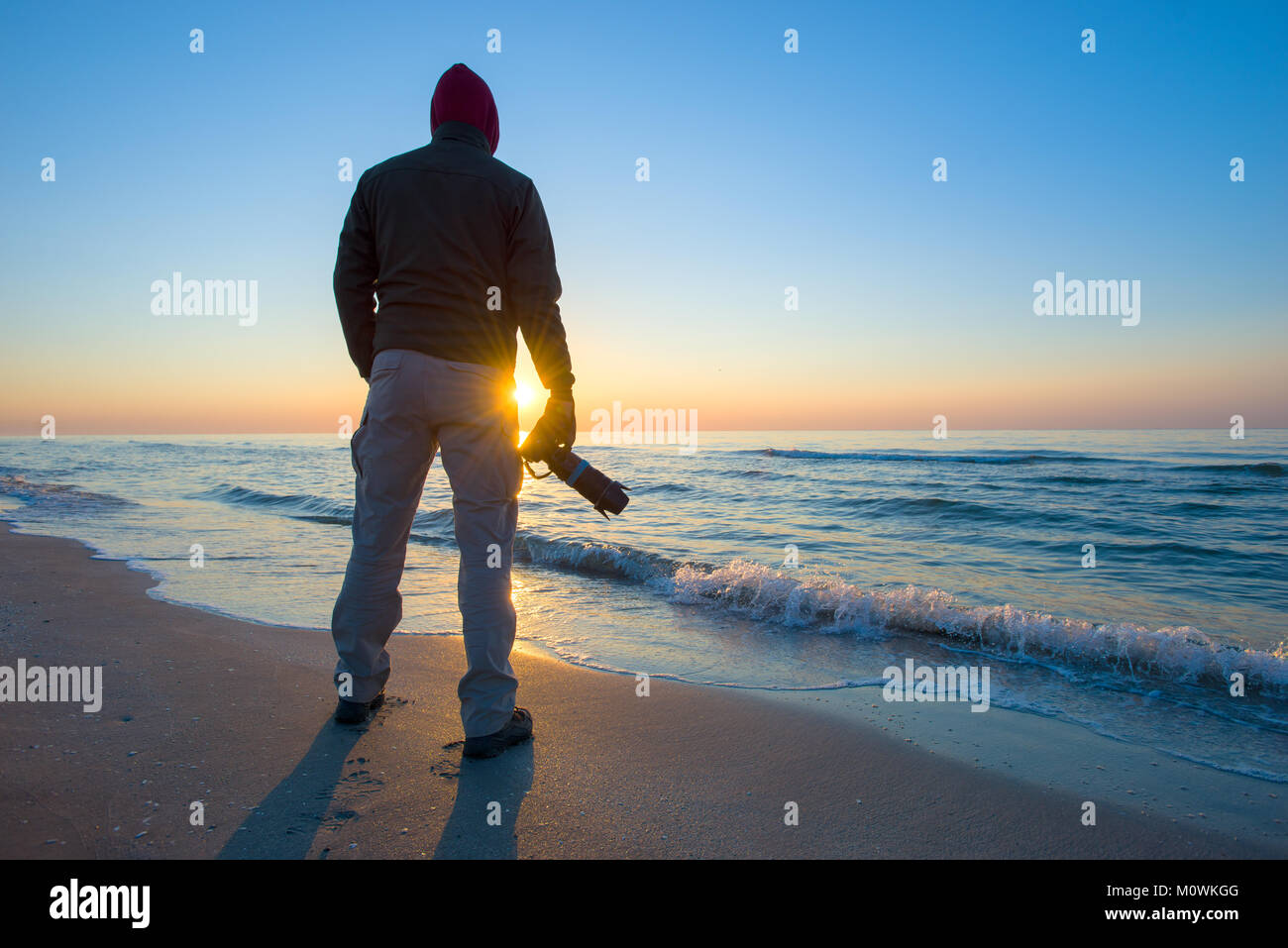 Der Mensch ist das Fotografieren einen Sonnenaufgang vor dem Hintergrund des Meeres. Stockfoto
