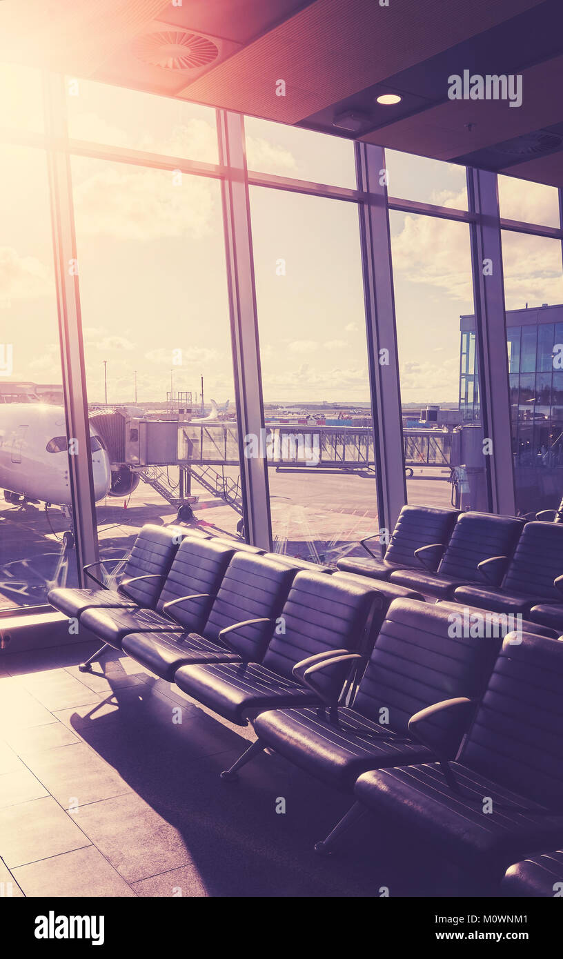 Leere Sitze in der Abflughalle am Flughafen bei Sonnenuntergang, Farbe getonte Reisen und Transport Konzept Bild mit Lens flare Effekt. Stockfoto