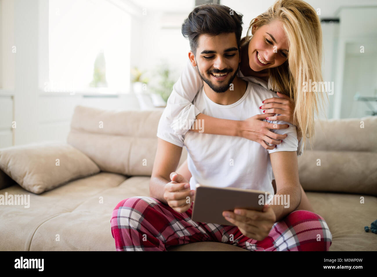 Glückliches Paar in der Liebe mit Tablet im Schlafanzug Stockfoto