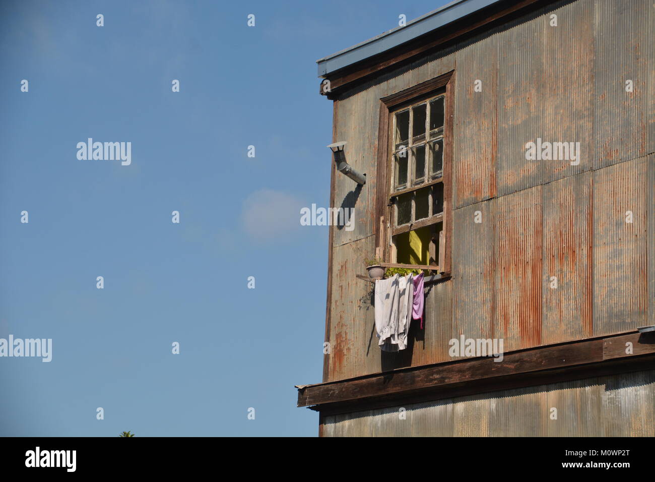 Das einfache Leben: Fenster in die Blau von einem städtischen rustikales Haus Wellblech Stockfoto