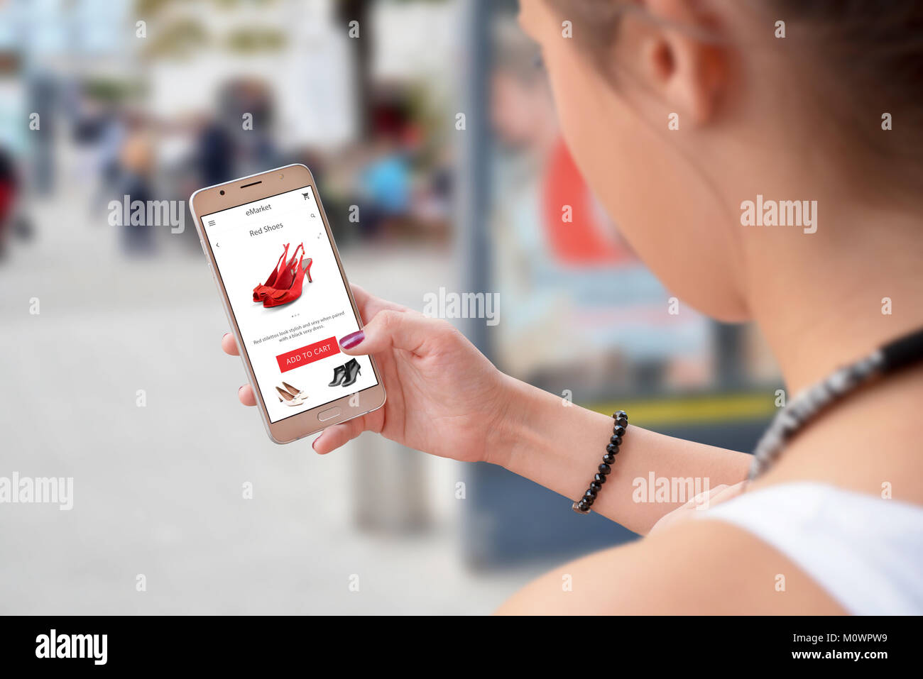 Frau online kaufen mit Shopping App auf Smart Phone. Stadt Straße im Hintergrund. Stockfoto