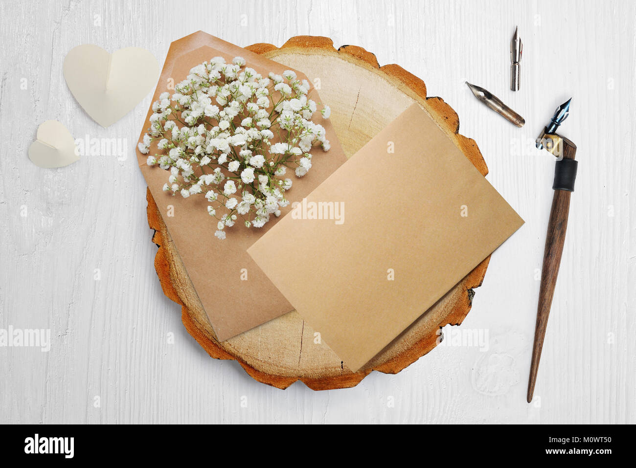 Kalligrafische Feder, liegt in der Nähe eines Holz- Kreis mit weißem Papier Herzen. Grußkarte für Valentines Tag mit Platz für Ihren Text. Flach, Ansicht von oben Foto Mock up Stockfoto