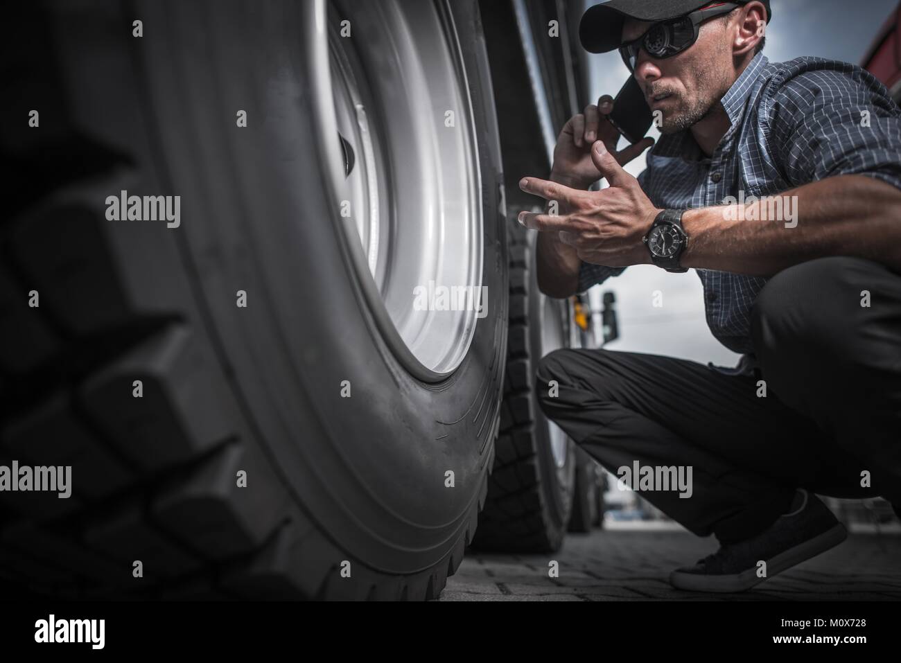 Lkw-Fahrer Bestellung neue Räder für seine Semi Truck. Kaukasische Arbeiter Telefon Gespräch, während Sie auf der Rückseite von seinem Anhänger Achse. Stockfoto