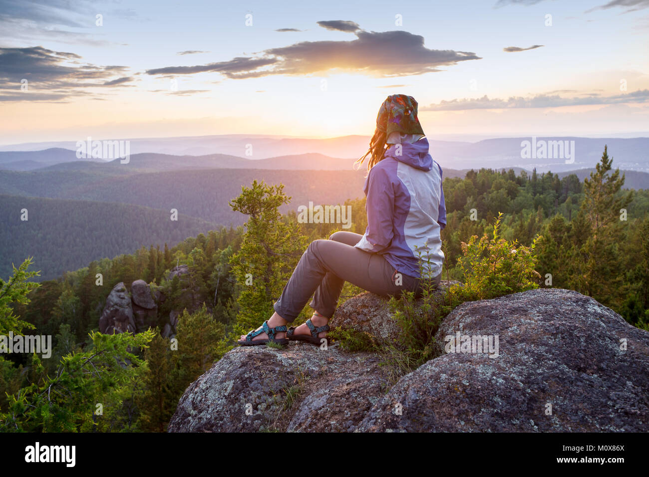 Junge Frau sitzt auf einem Felsen, der Horizont der Suche Stockfoto