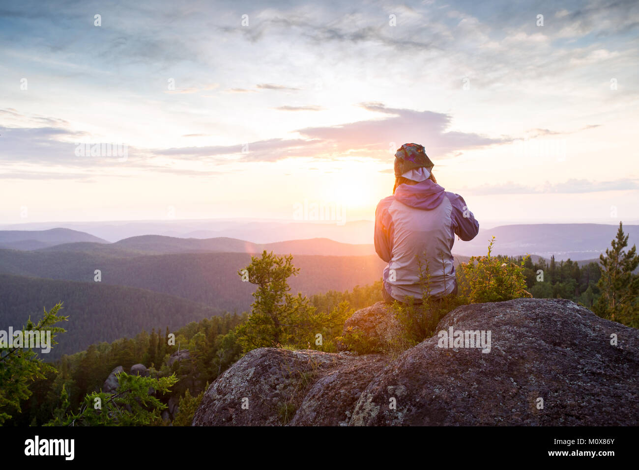 Junge Frau sitzt auf einem Felsen, der Horizont der Suche Stockfoto
