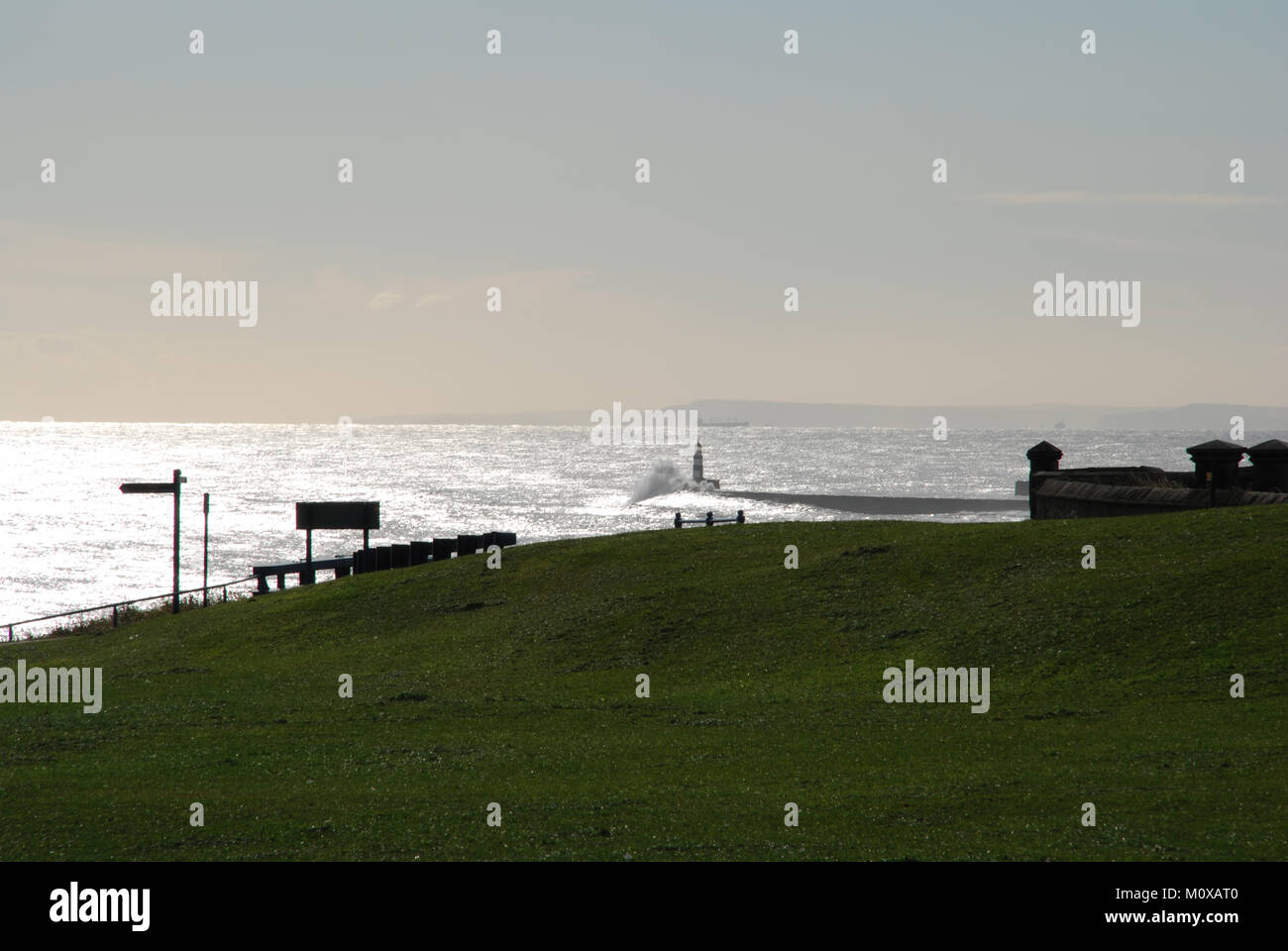 Leuchtturm und Pier von Seaham Harbour von Clifftop mit Wellen, die über den Pier brechen Stockfoto