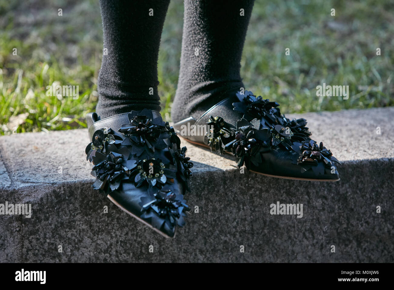 Mailand - Januar 13: Frau mit niedrigen, schwarzen Leder Schuhe mit Blumen Dekoration vor dem Emporio Armani Fashion Show, Mailand Fashion Week street style Stockfoto