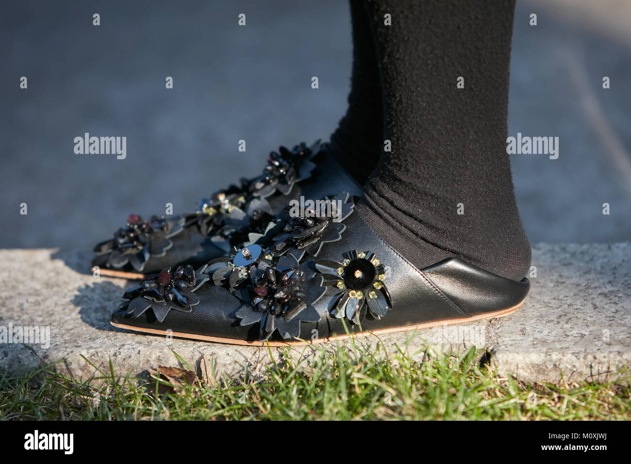 Mailand - Januar 13: Frau mit niedrigen, schwarzen Leder Schuhe mit Blumen Dekoration vor dem Emporio Armani Fashion Show, Mailand Fashion Week street style Stockfoto