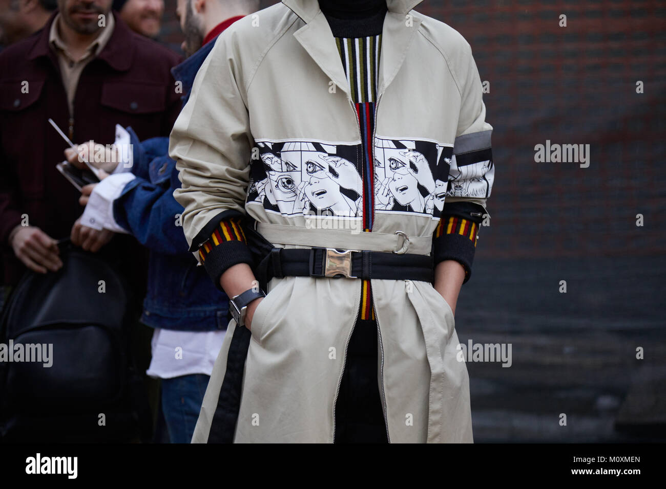 Mailand - Januar 13: Mann mit beigefarbenen Trenchcoat mit Comics Dekoration vor Neil Barrett fashion show, Mailand Fashion Week street style am 13. Januar Stockfoto