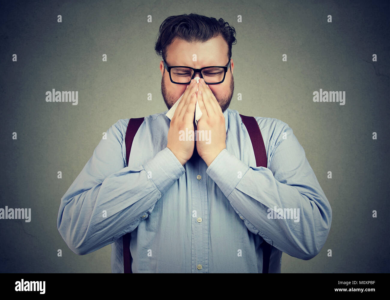 Junge mollig Mann Leiden von der Grippe seine Nase weht mit Serviette. Stockfoto