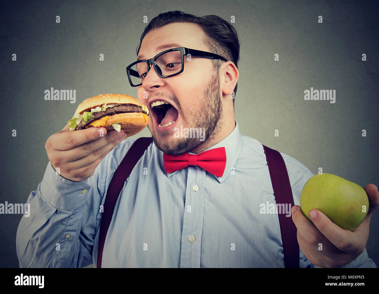 Mollig Mann in Brillen Burger essen Auswahl von Junk food anstelle der gesunden Ernährung. Stockfoto