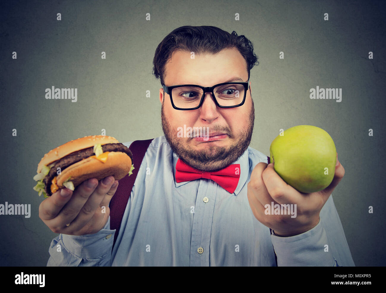 Übergewichtigen Mann, Hamburger und green apple Probleme mit Diät Wahl. Stockfoto