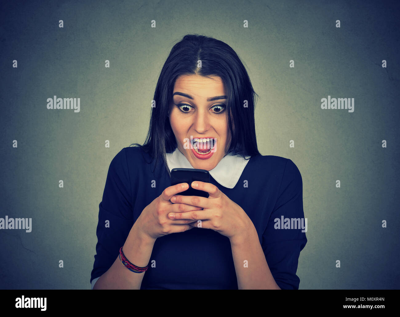 Junge super aufgeregt Frau suchen bei smartpone können zufrieden mit schockierenden Nachrichten. Stockfoto